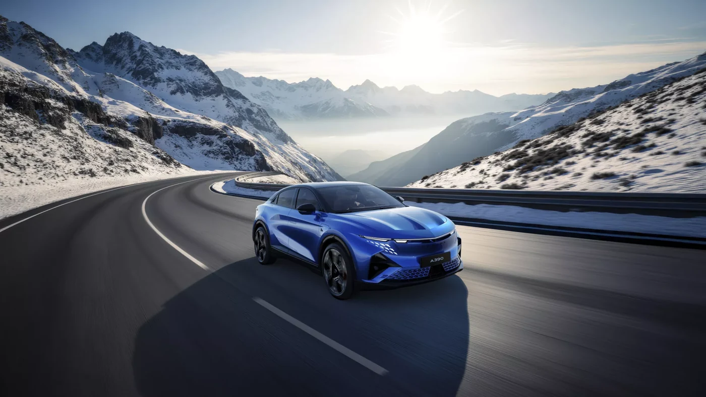 Alpine A390 bleue sur une route de montagne entourée de sommets enneigés