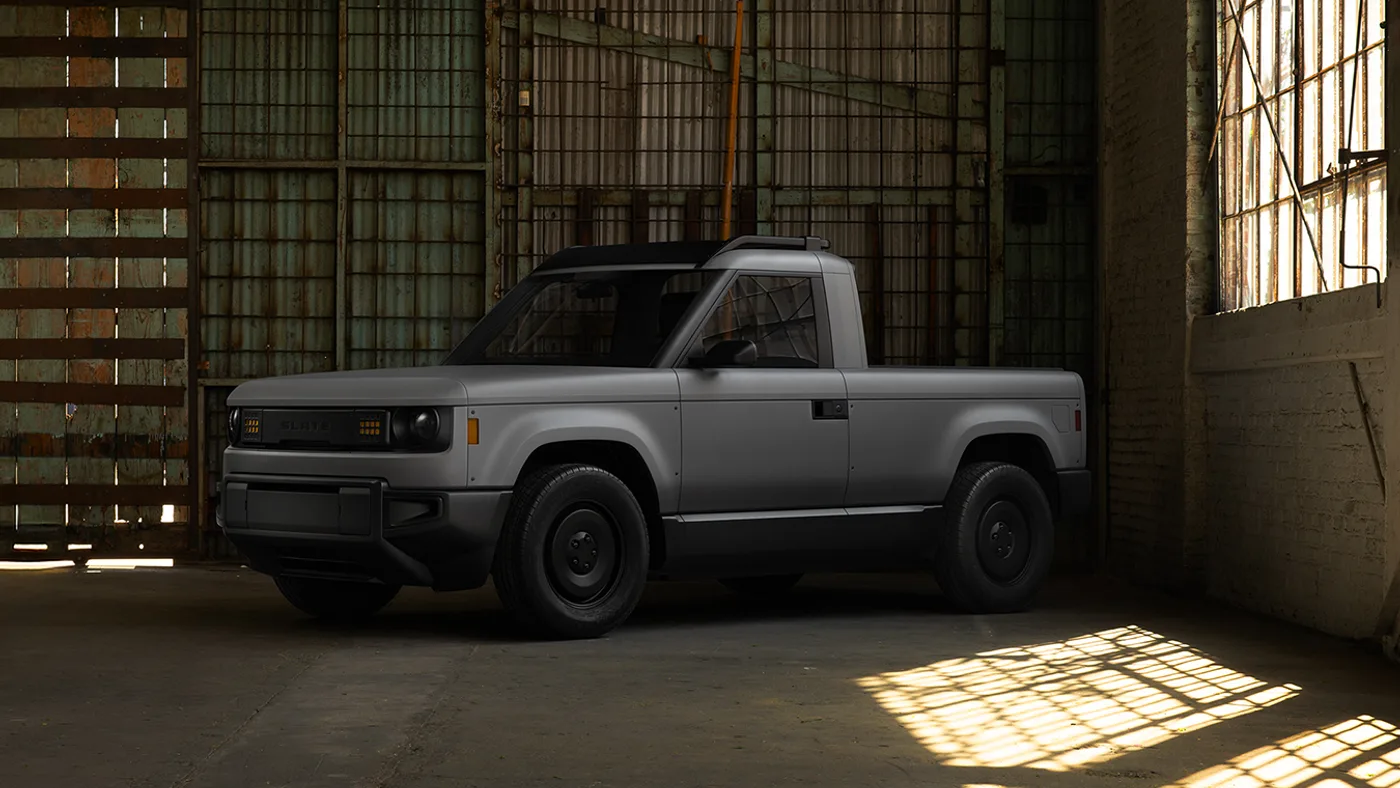 Pick-up Slate gris mat à deux portes, vu de trois quarts avant dans un entrepôt aux fenêtres industrielles, une flaque de soleil au sol.